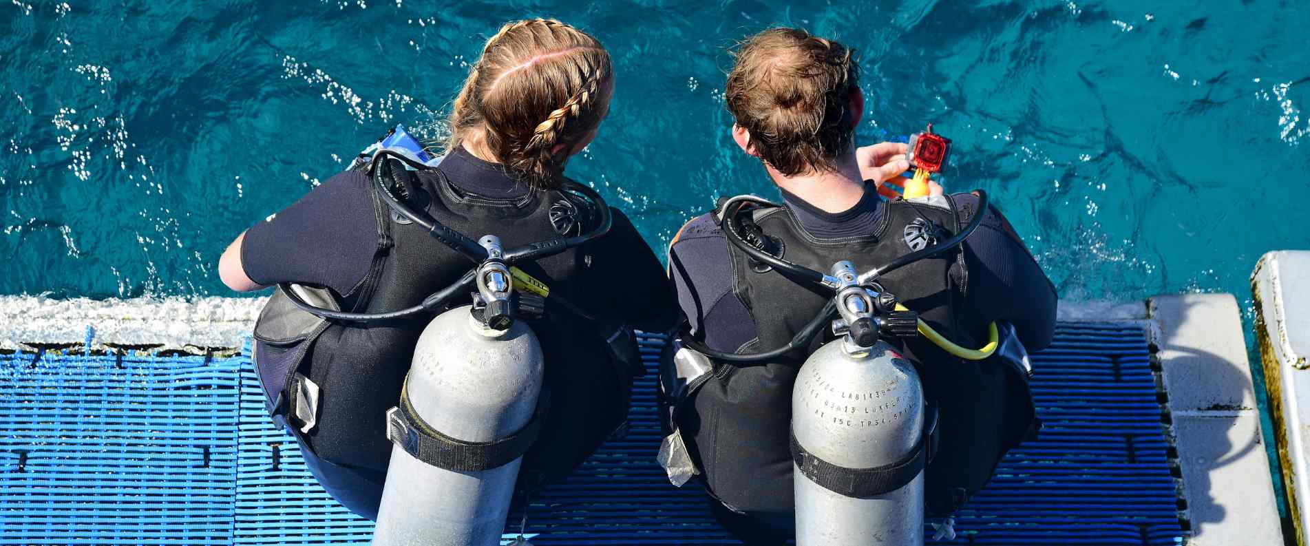 Stwo people sitting on edge of boat about to snorkle