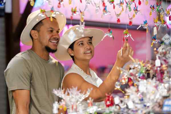 Two people looking at items from a market stall at Cairns Night Market